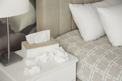 Photo of Used paper tissues and holder on table in bedroom