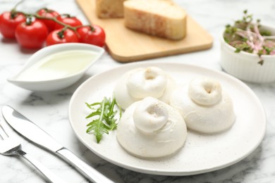 Photo of Delicious burrata cheese with arugula on white marble table, closeup