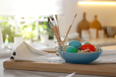 Photo of Beautifully painted Easter eggs in bowl on table indoors