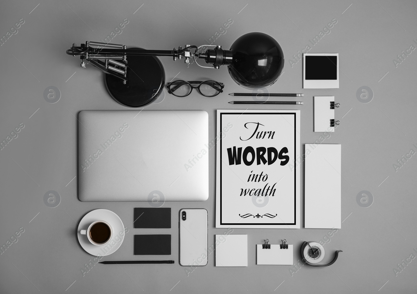 Image of Card with phrase Turn Words Into Wealth, laptop and stationery on grey table, flat lay