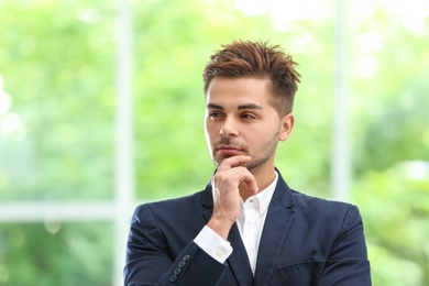 Portrait of handsome young man in elegant suit against window