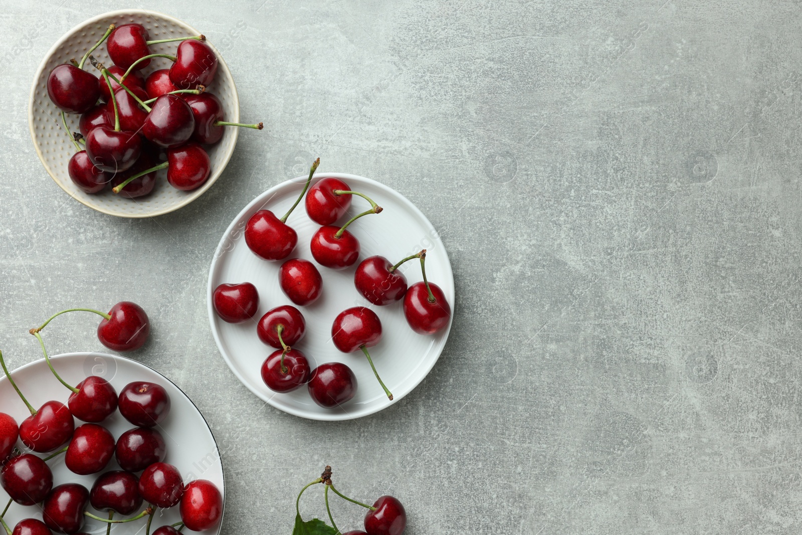 Photo of Fresh ripe cherries on light grey table, flat lay. Space for text