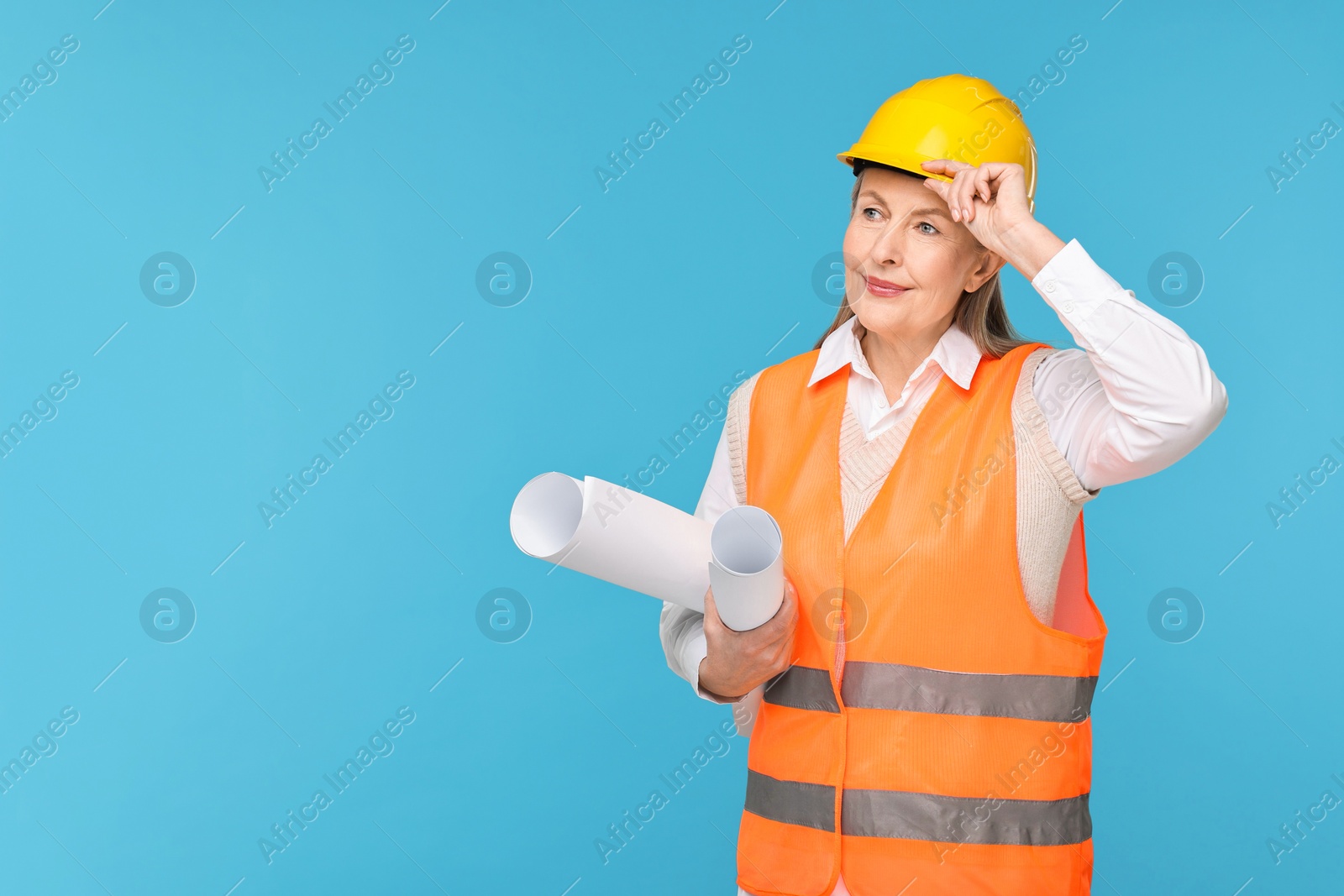 Photo of Architect in hard hat with drafts on light blue background, space for text