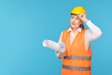 Photo of Architect in hard hat with drafts on light blue background, space for text