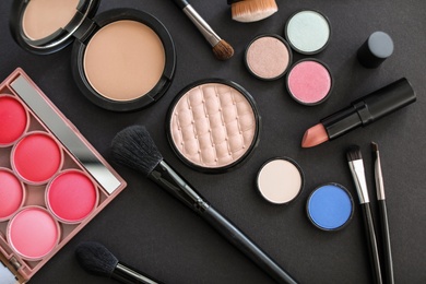 Photo of Flat lay composition with makeup brushes and cosmetic products on black background