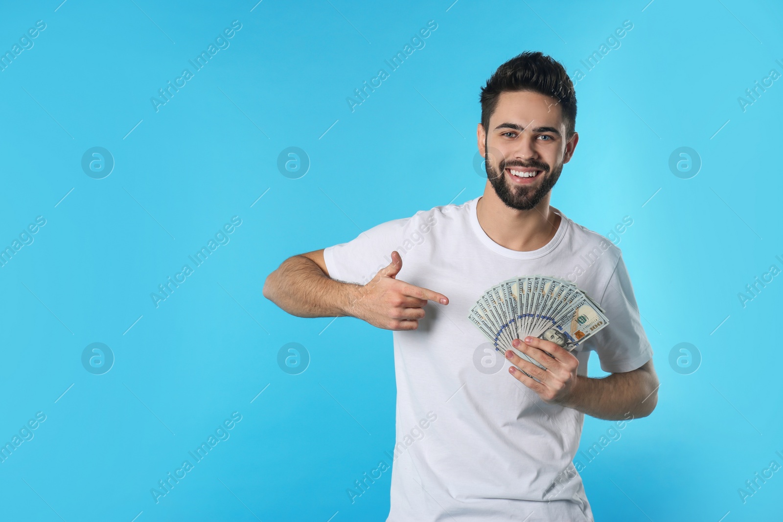 Photo of Portrait of happy young man with money on color background. Space for text