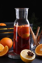 Photo of Aromatic punch drink and ingredients on black table