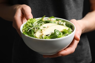 Photo of Woman holding bowl with fresh pear salad, closeup