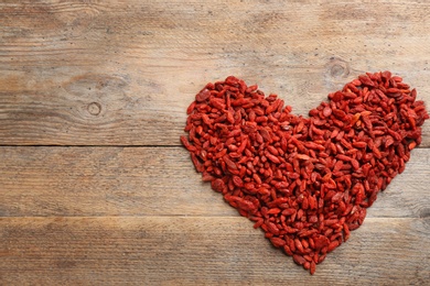 Photo of Heart made of dried goji berries on wooden table, top view with space for text. Healthy superfood