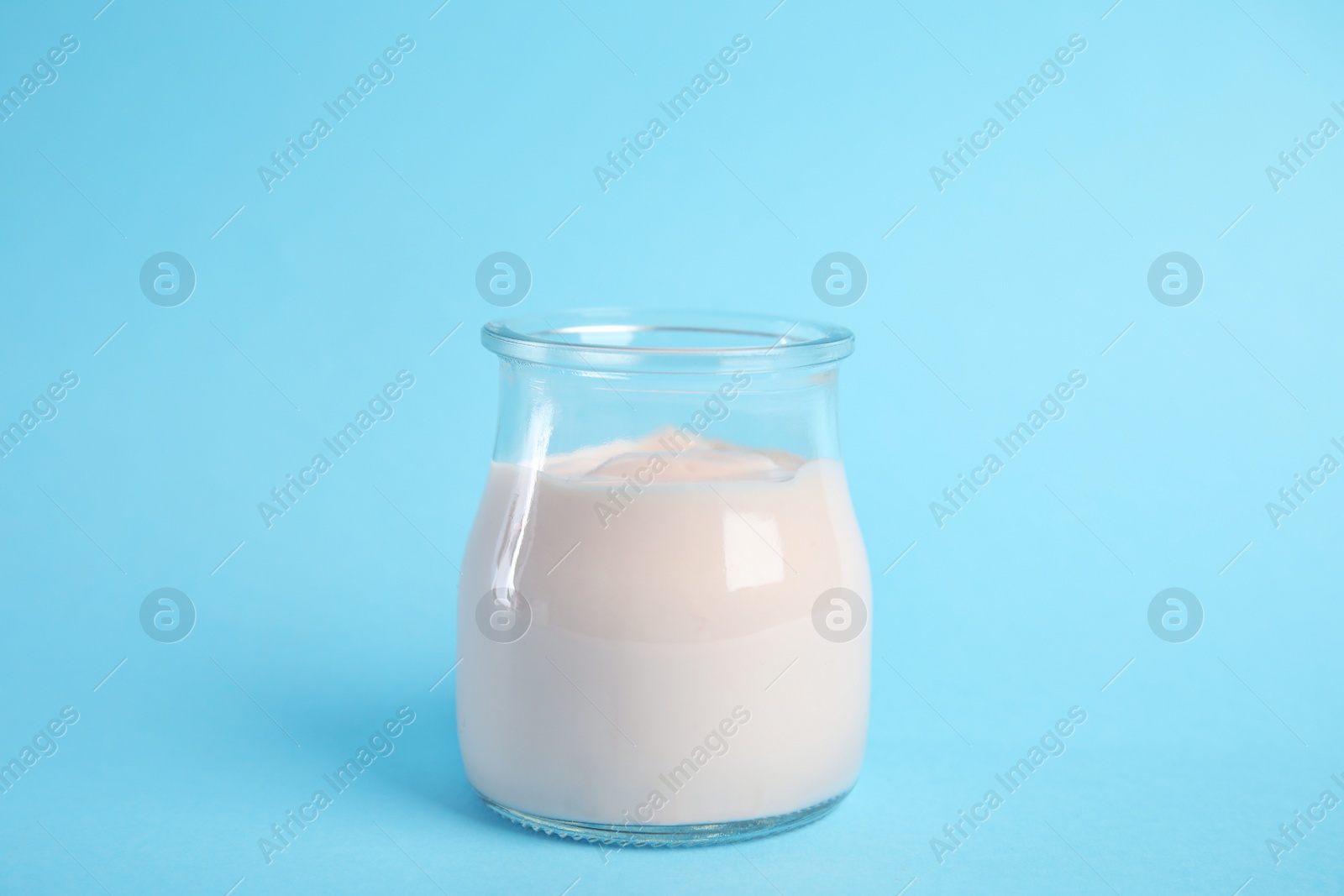 Photo of Tasty organic yogurt on light blue background