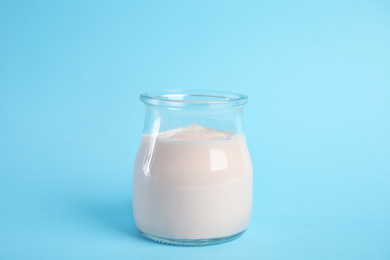 Photo of Tasty organic yogurt on light blue background