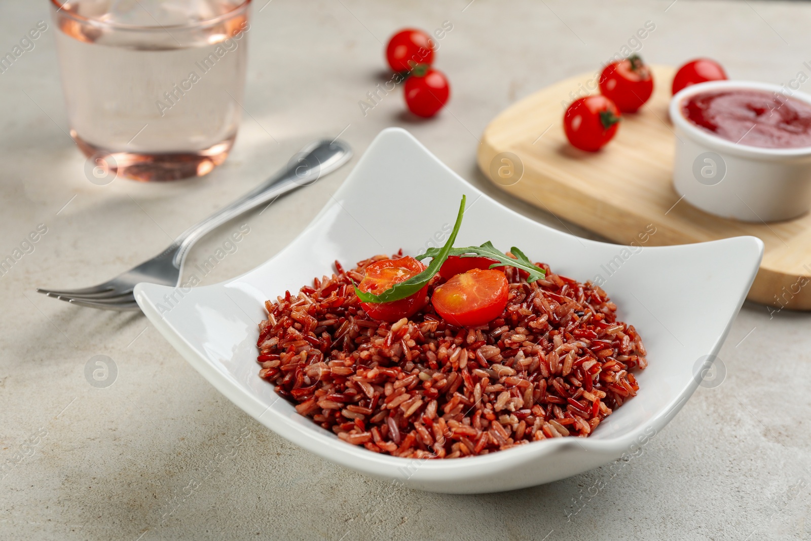 Photo of Tasty brown rice with tomatoes on light grey table