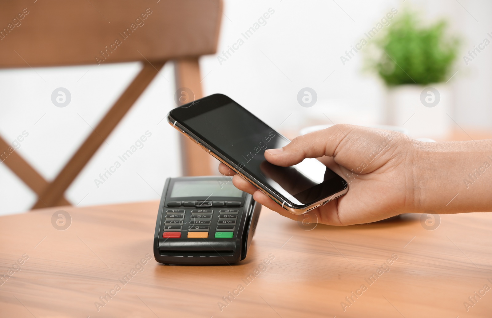 Photo of Woman using terminal for contactless payment with smartphone in cafe