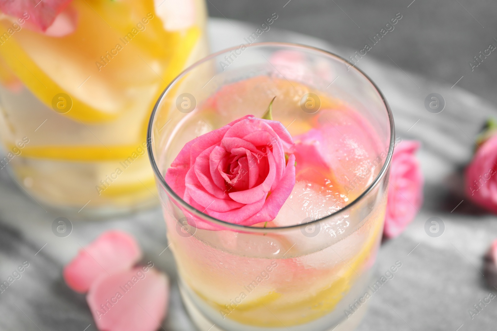 Photo of Delicious refreshing drink with lemon and rose on grey table, closeup