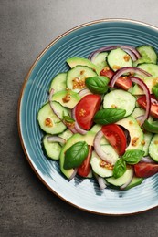 Photo of Tasty salad with cucumbers on grey table, top view