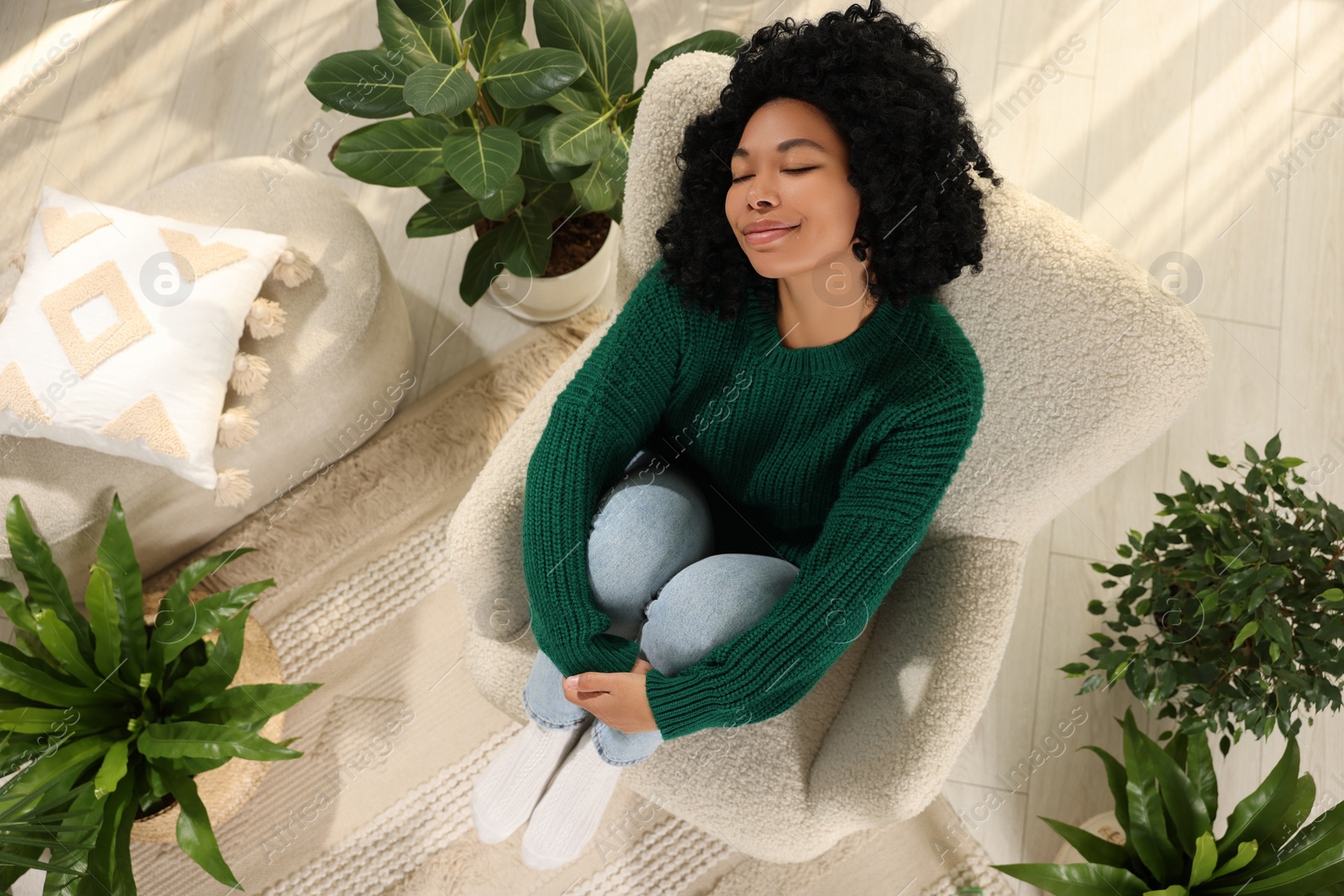 Photo of Woman relaxing near beautiful houseplants in room, above view