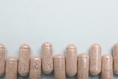 Photo of Many gelatin capsules on light grey background, flat lay. Space for text