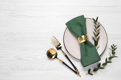 Photo of Stylish setting with cutlery and eucalyptus leaves on white wooden table, flat lay. Space for text