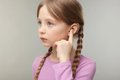 Little girl with hearing aid on grey background