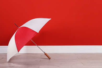 Photo of Beautiful colorful umbrella near red wall. Space for text