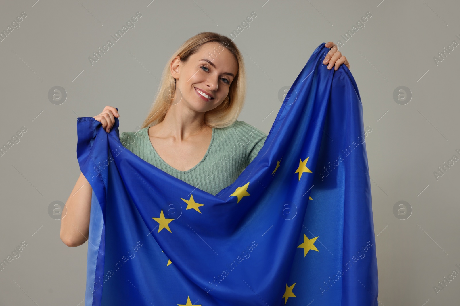 Photo of Happy woman with flag of European Union on grey background