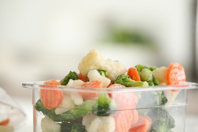Photo of Mix of different frozen vegetables in plastic container, closeup. Space for text