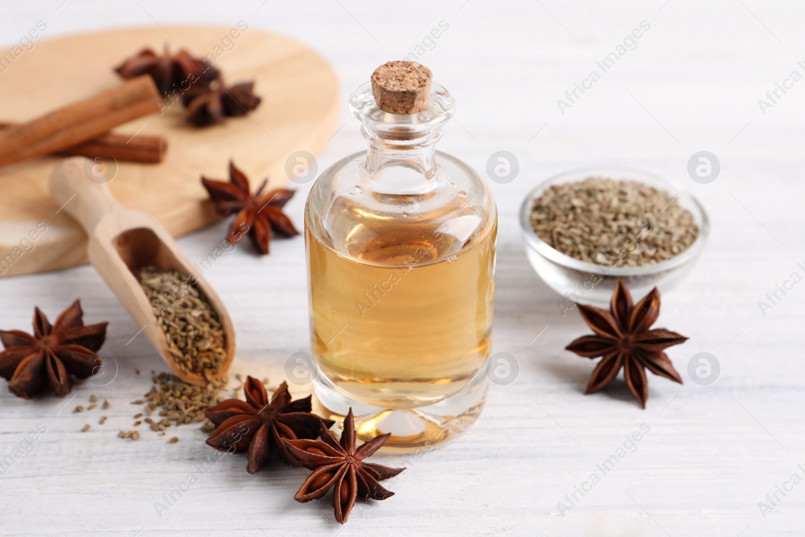 Photo of Bottle of essential oil, anise and seeds on white wooden table