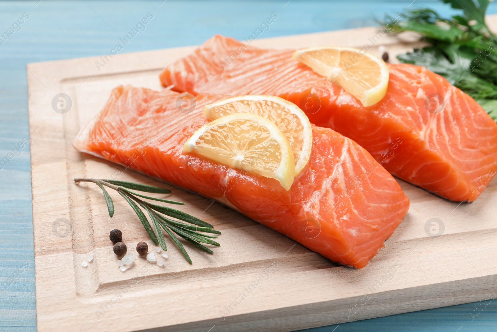 Photo of Fresh salmon and ingredients for marinade on light blue wooden table, closeup