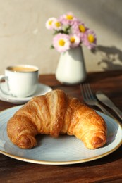 Delicious fresh croissant served with coffee on wooden table