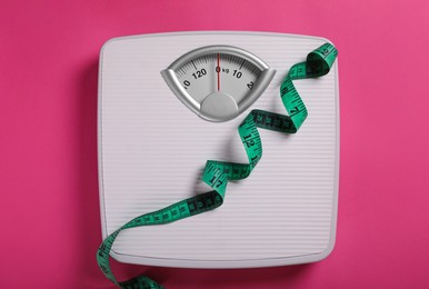 Photo of Weight loss concept. Scales and measuring tape on pink background, top view