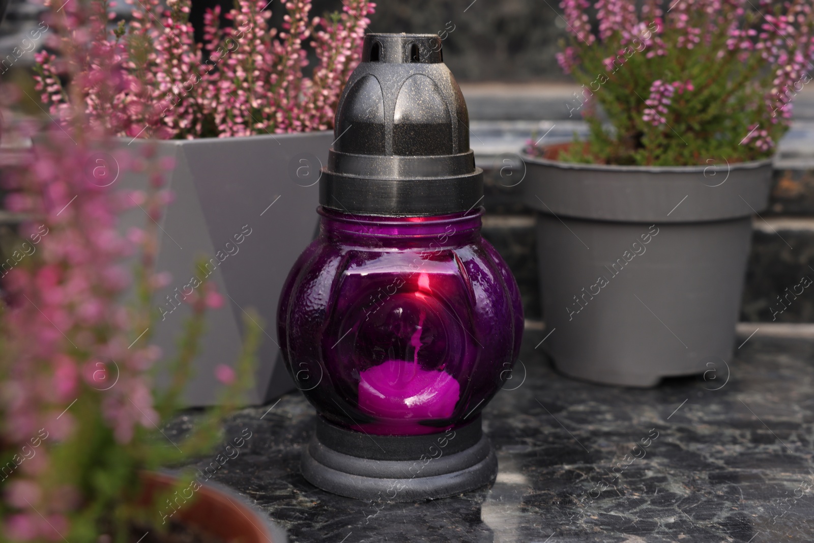 Photo of Grave lantern on grey granite surface at cemetery