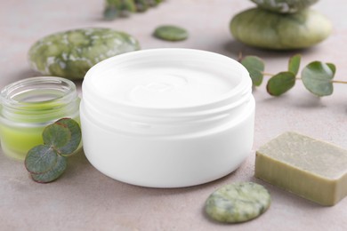 Jars of cream, soap, spa stones and green leaves on light textured table, closeup. Body care products