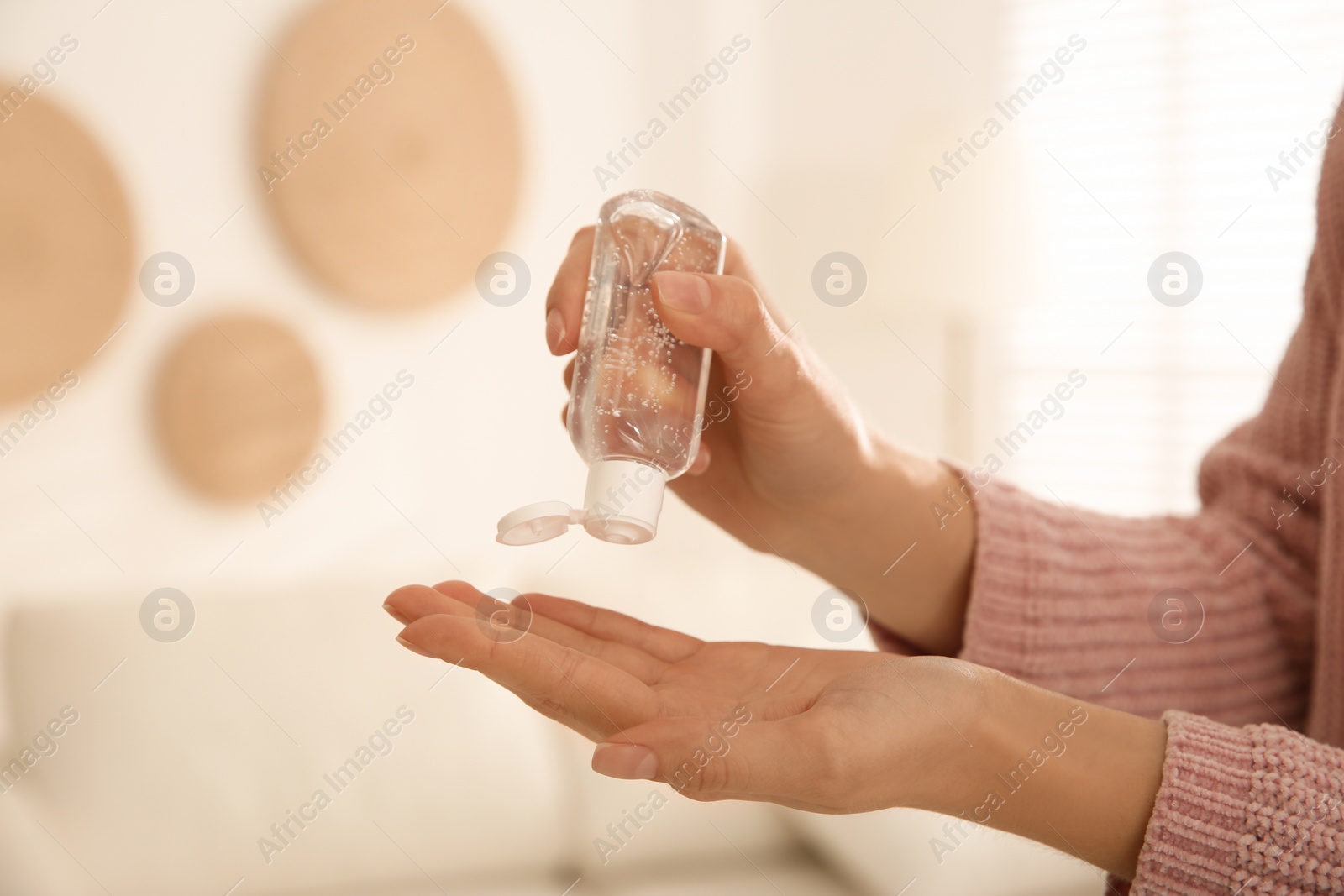 Photo of Woman applying antiseptic gel at home, closeup