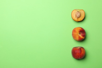 Photo of Sweet juicy peaches on green background, top view. Space for text