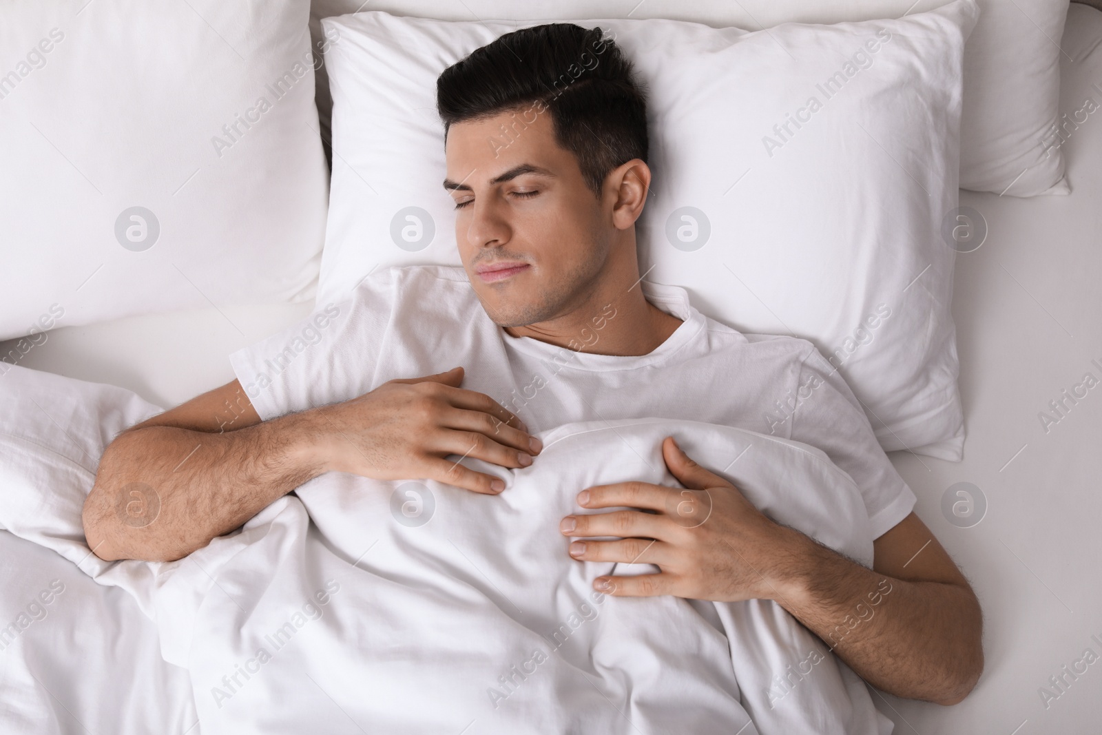 Photo of Handsome man sleeping in bed at home, top view