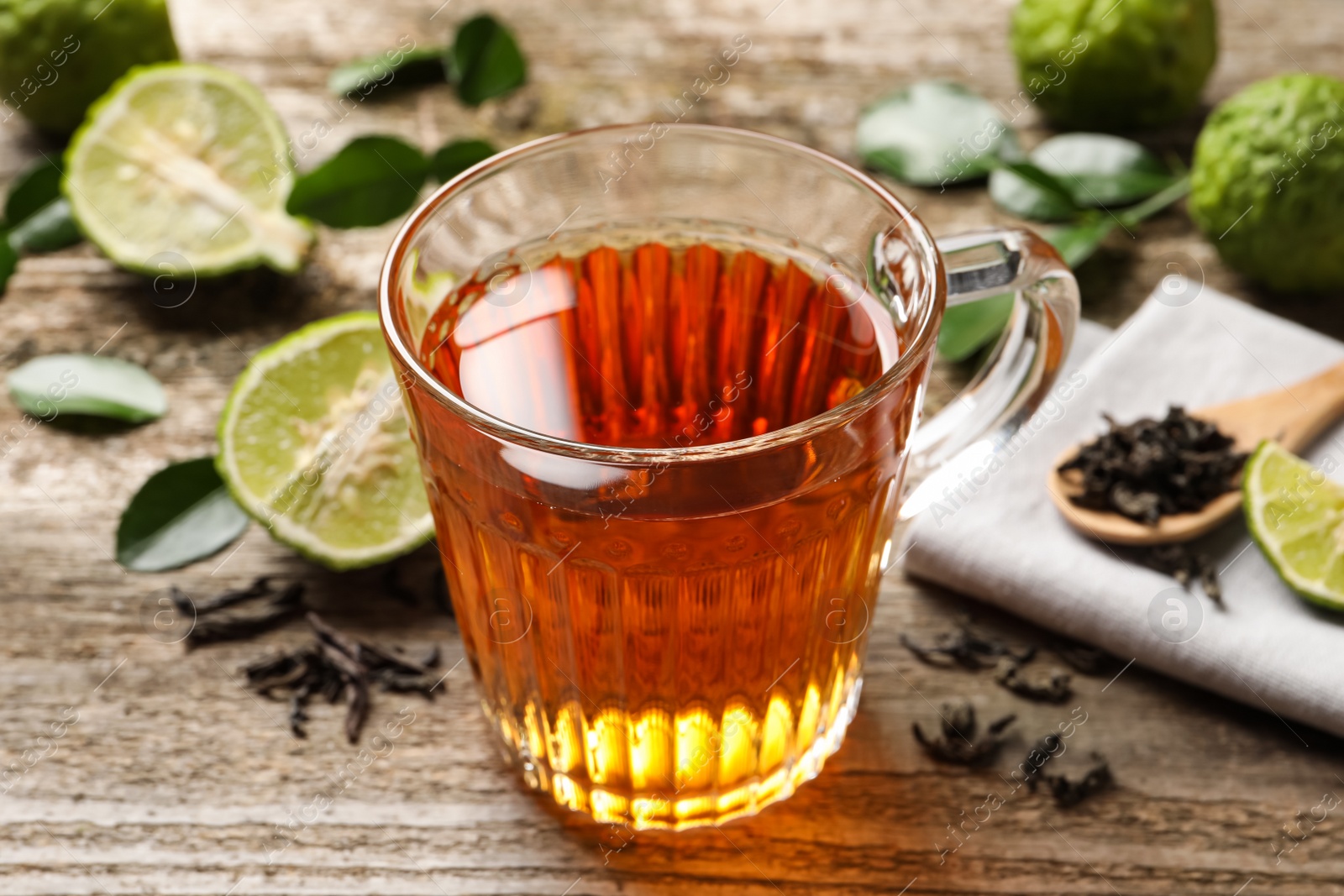 Photo of Glass cup of tasty bergamot tea on wooden table, closeup