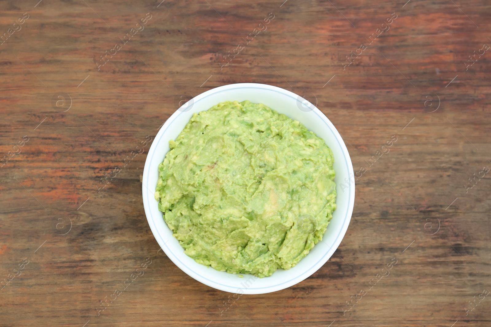 Photo of Delicious guacamole made of avocados on wooden table, top view