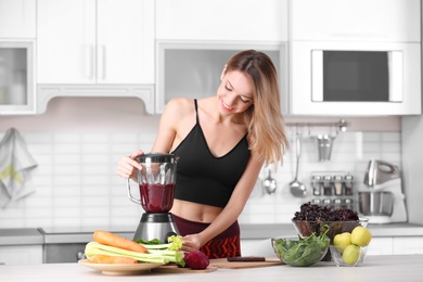 Young woman preparing tasty healthy smoothie at table in kitchen