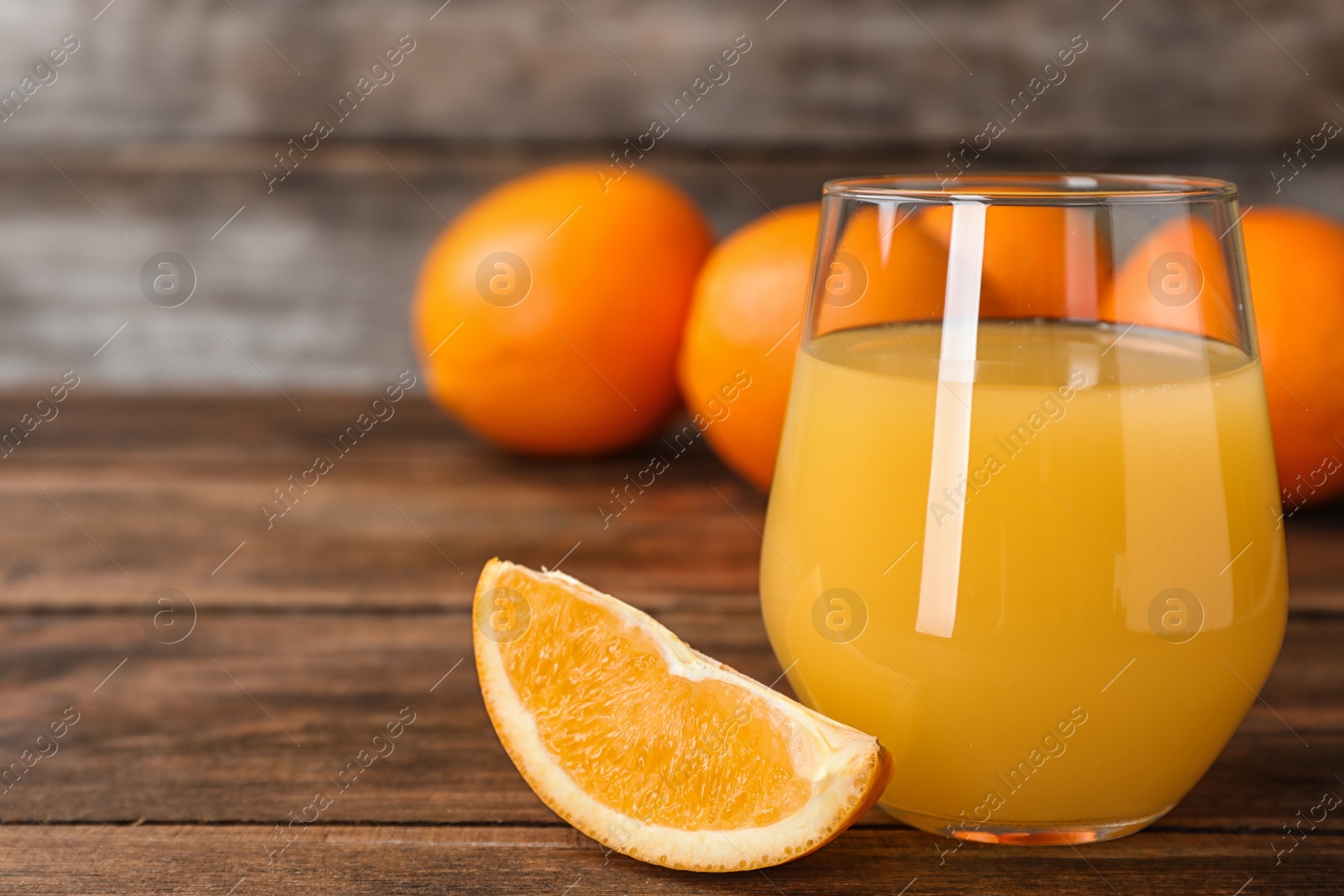 Photo of Glass of orange juice and slice of fresh fruit on wooden table. Space for text