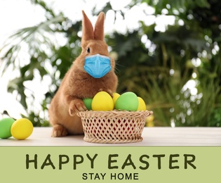 Text Happy Easter Stay Home and cute bunny in protective mask on white table outdoors. Holiday during Covid-19 pandemic