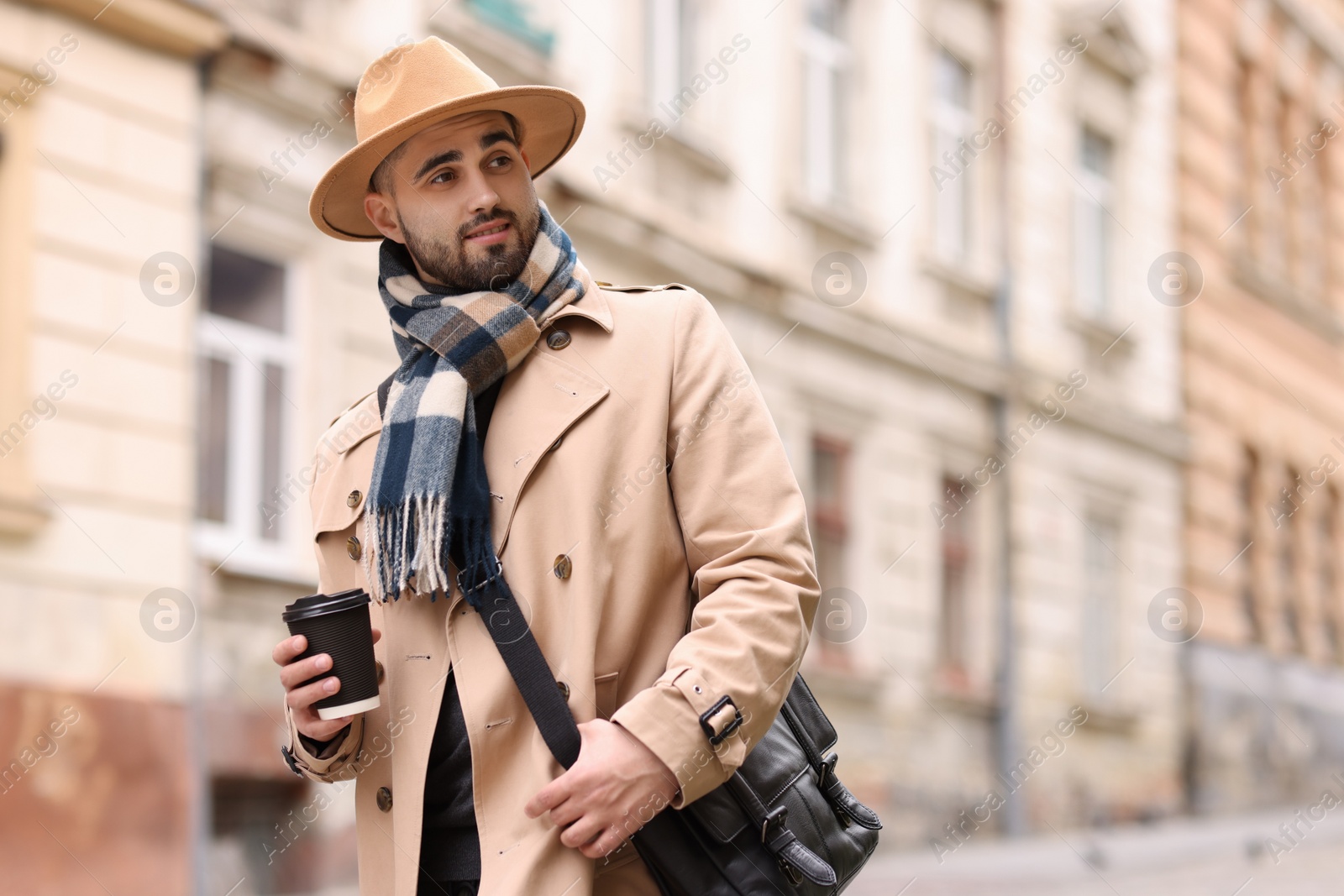 Photo of Handsome man in warm scarf with paper cup outdoors. Space for text