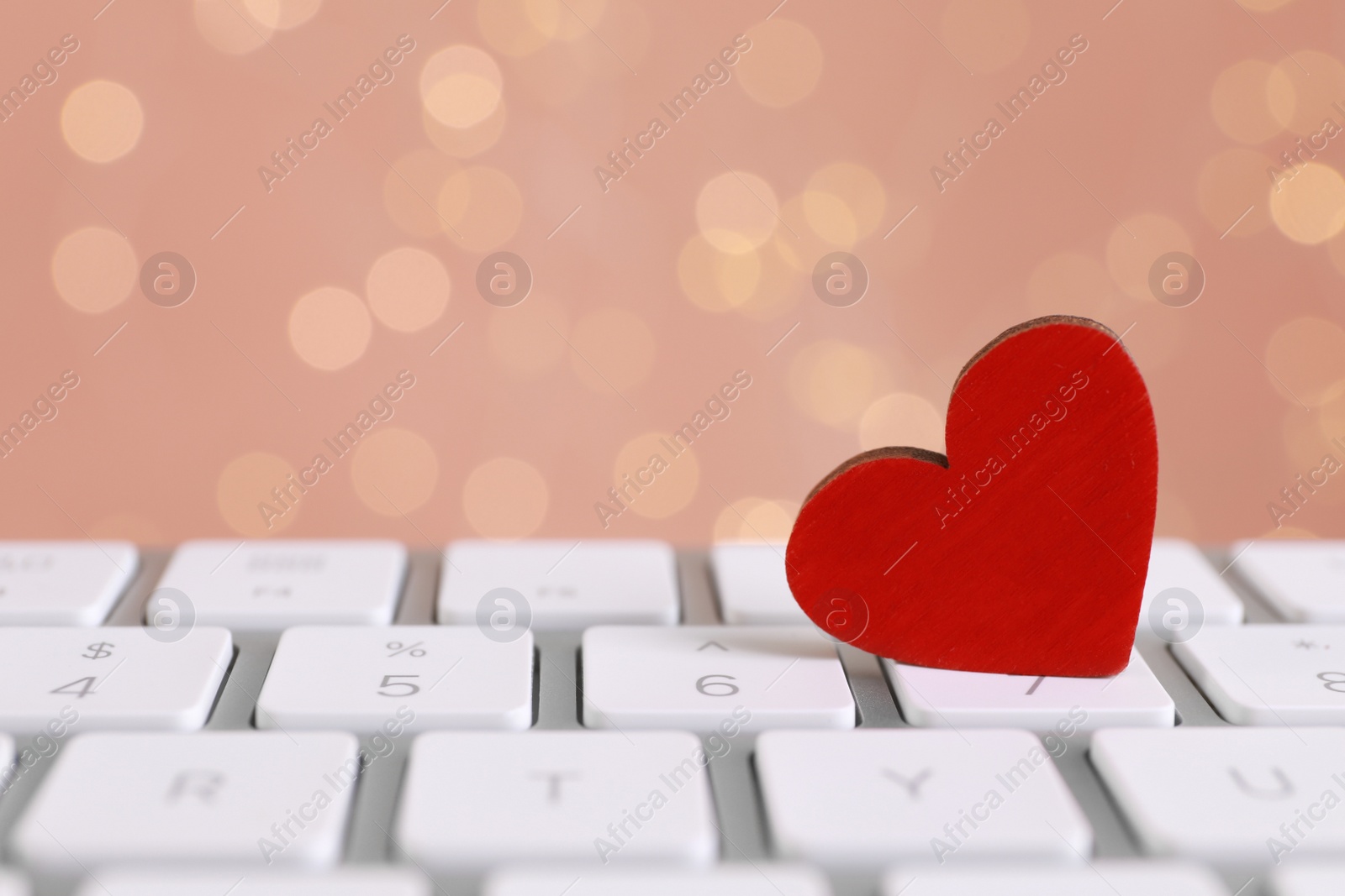 Photo of Red decorative heart on laptop keyboard, closeup. Online dating concept