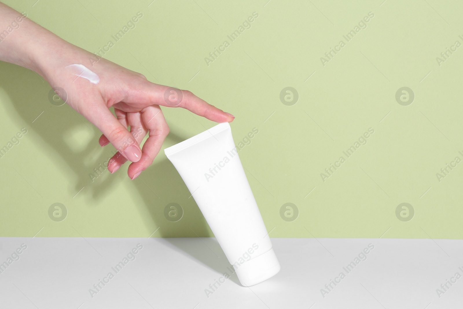 Photo of Woman with tube of cream on color background, closeup. Space for text