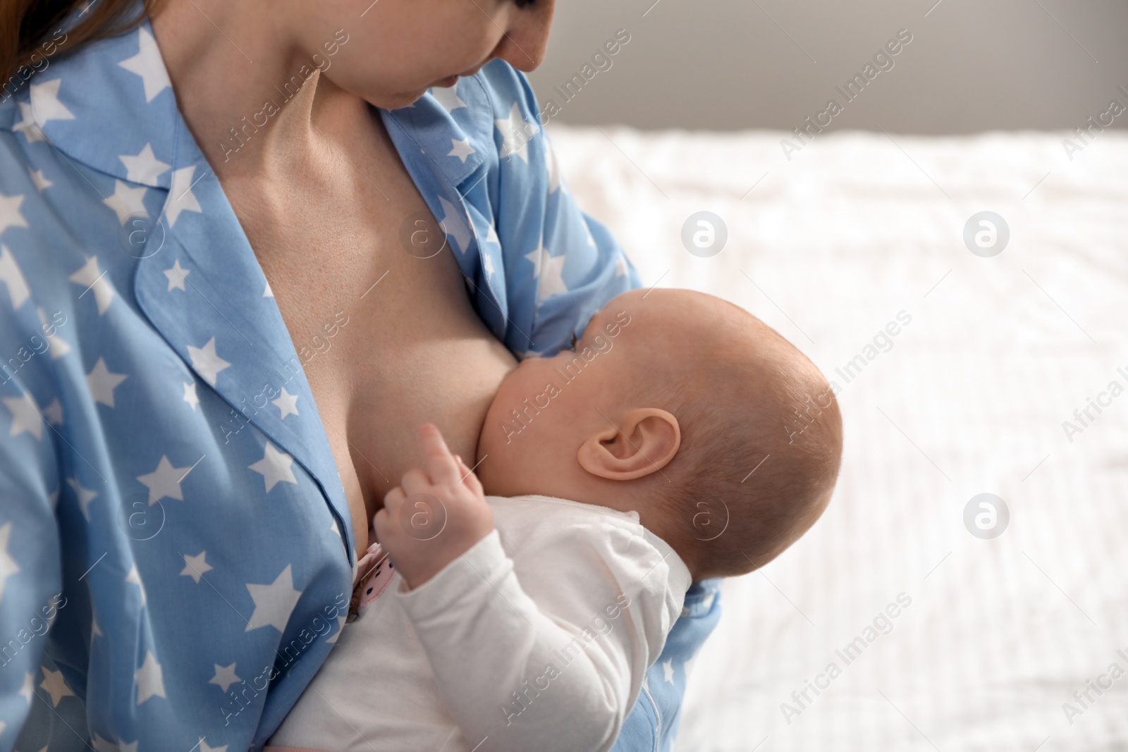 Photo of Young woman breast feeding her little baby on bed, closeup