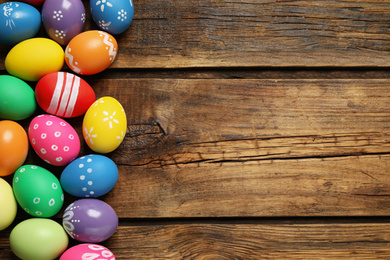 Photo of Colorful Easter eggs on wooden background, flat lay. Space for text