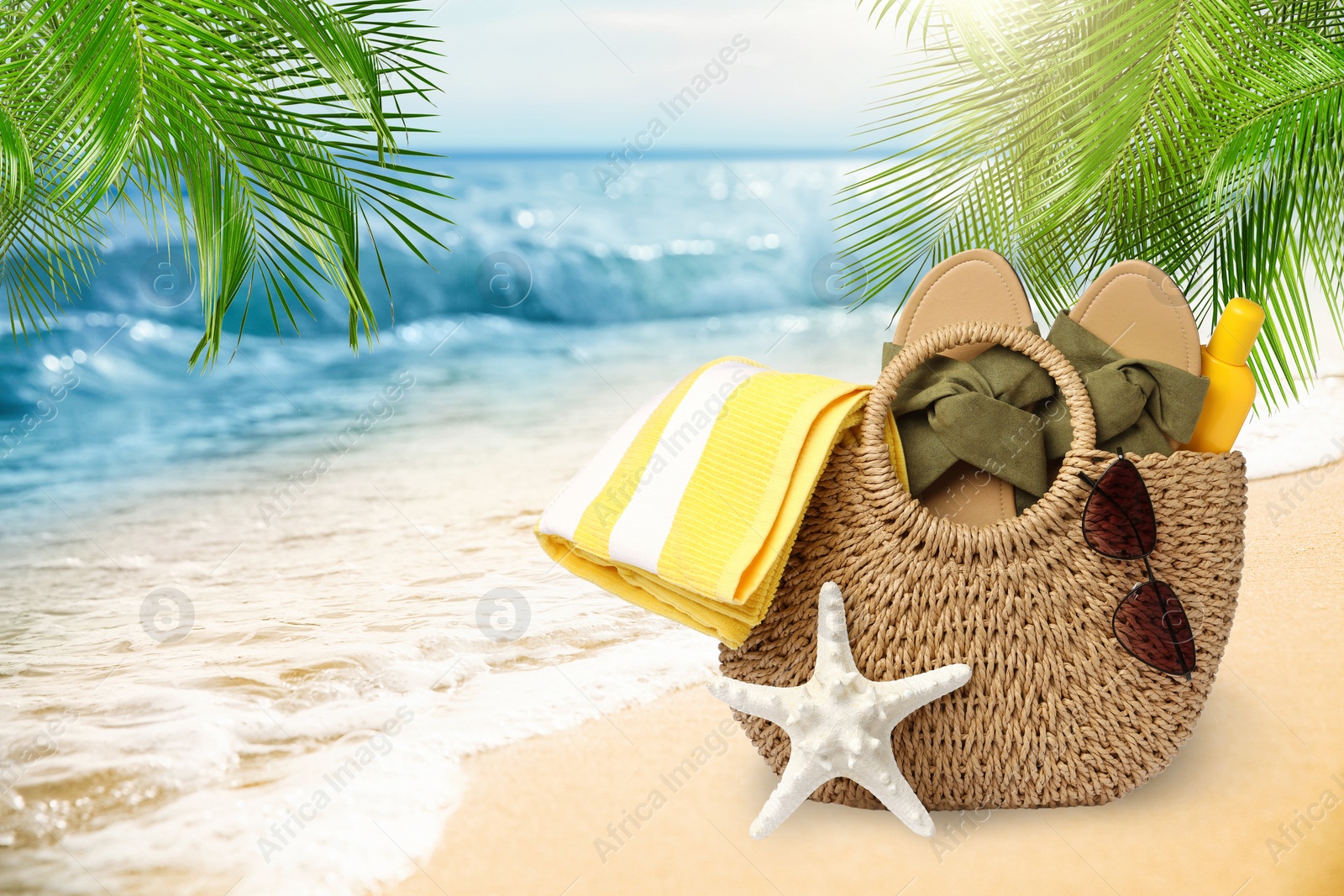 Image of Stylish bag with different accessories on tropical sandy beach, space for text 