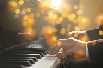 Image of Christmas and New Year music. Man playing piano, closeup. Bokeh effect
