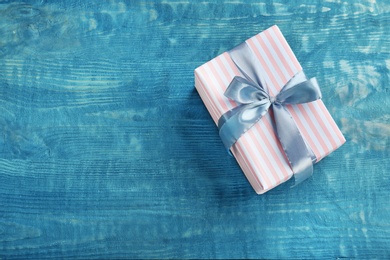 Elegant gift box with bow on wooden background, top view