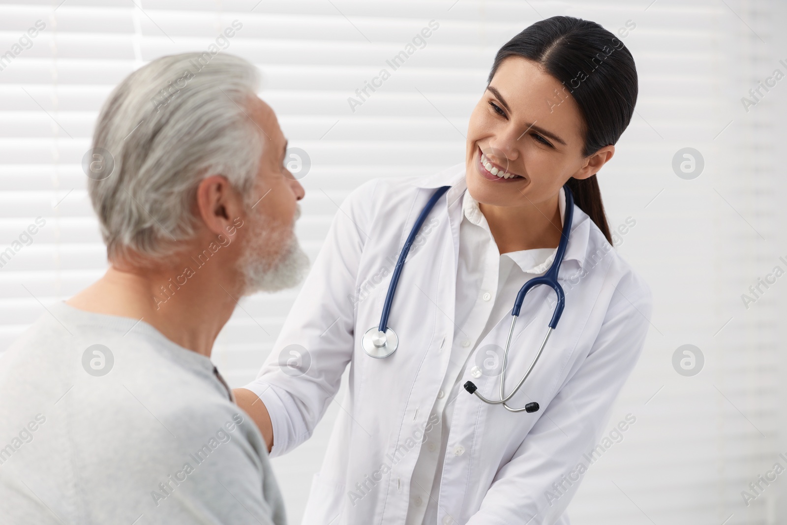 Photo of Smiling nurse supporting elderly patient in hospital