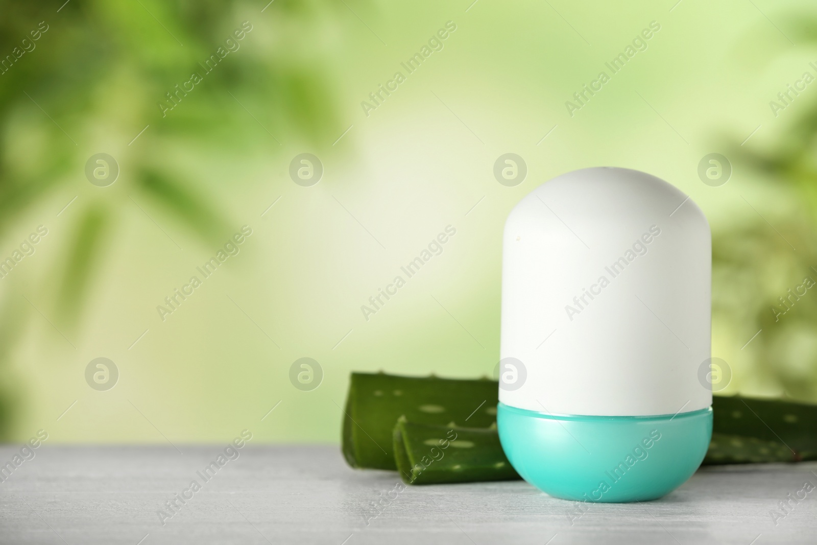 Photo of Deodorant container and aloe vera on white wooden table against blurred background. Space for text